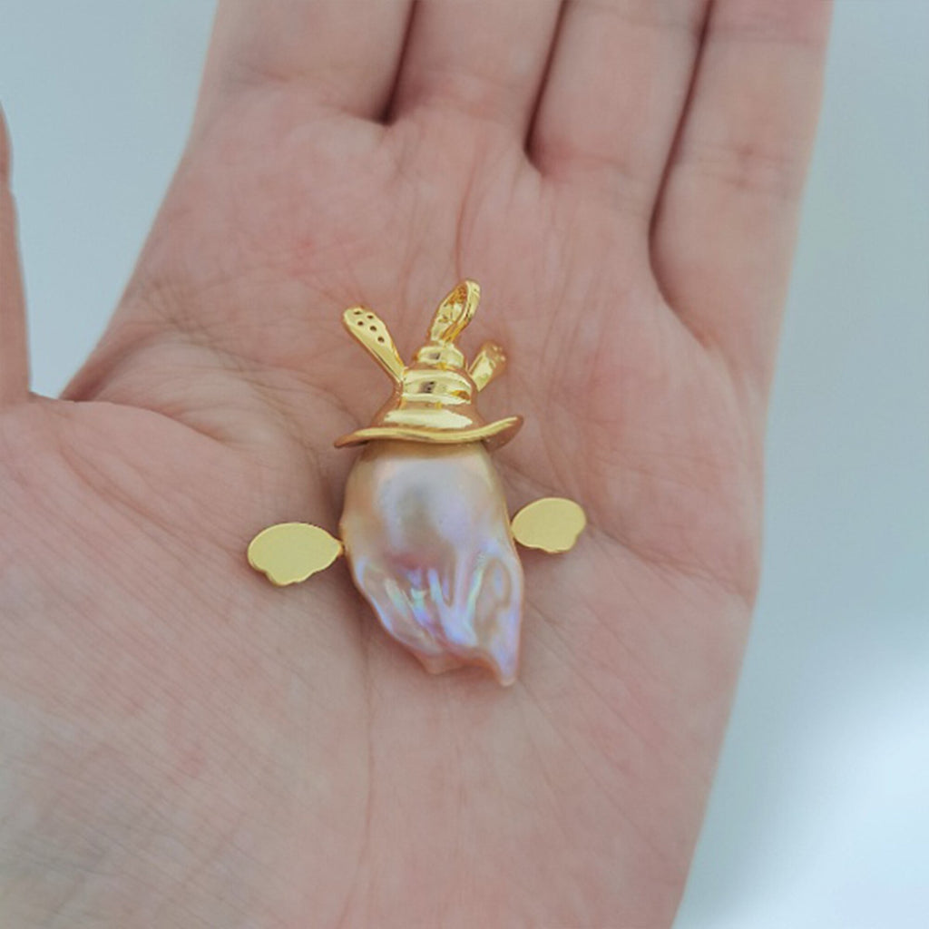 Gold pendant with a shell on a hand against a white background