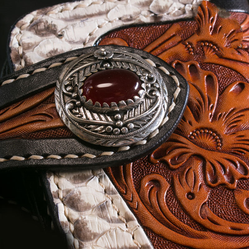 Close-up of a decorative leather belt with intricate patterns and a prominent buckle.