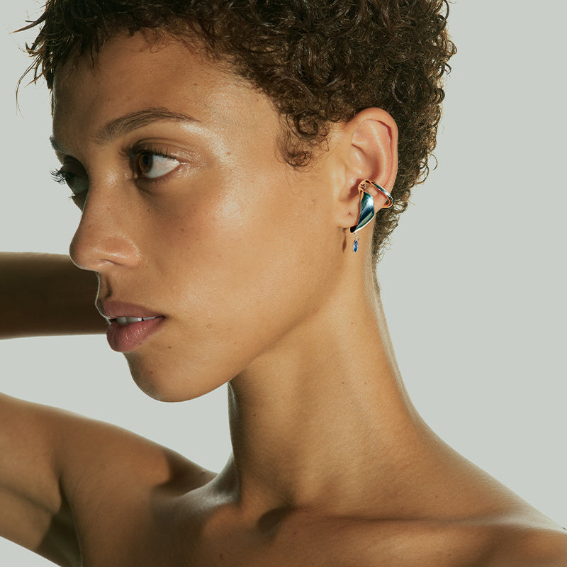 Close-up of a woman wearing a colorful earring against a neutral background