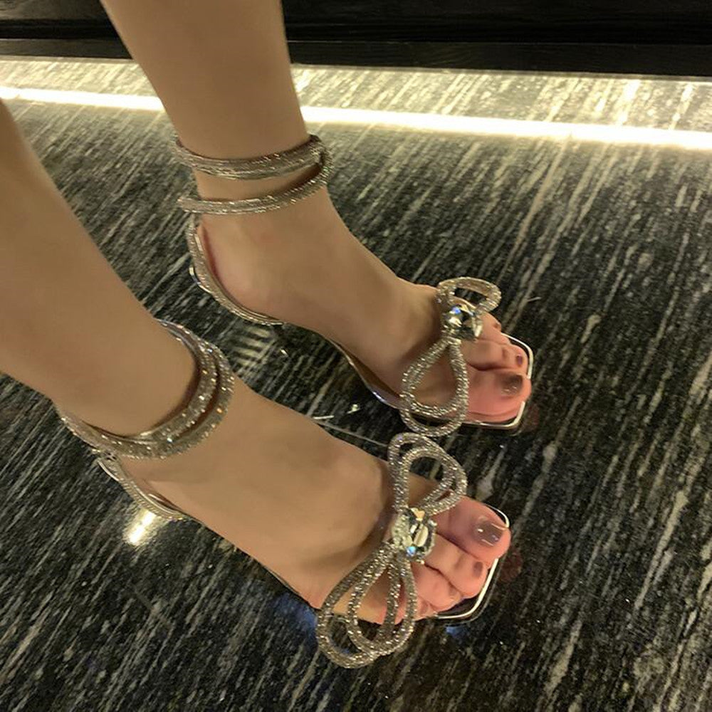 Silver strappy high-heeled sandals on a patterned floor