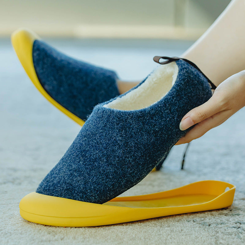 Blue slip-on shoes with yellow soles being worn indoors.