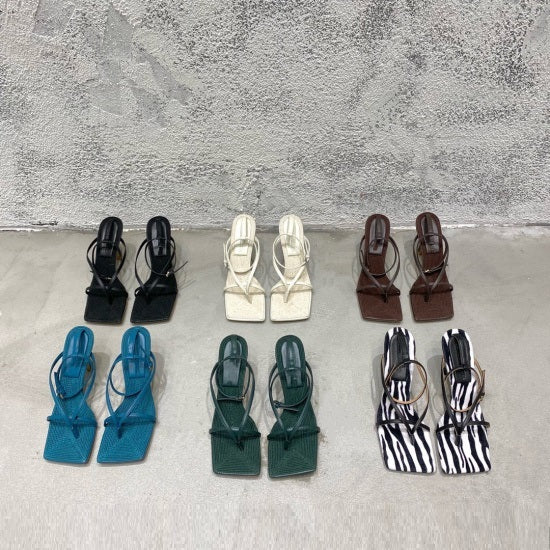 Collection of various colored sandals arranged on a textured surface.