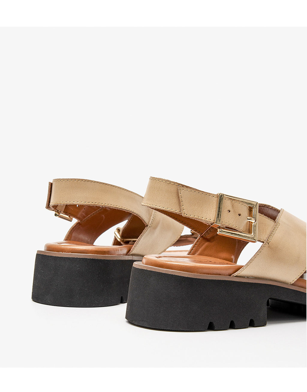 Beige sandals with black platforms on a white background
