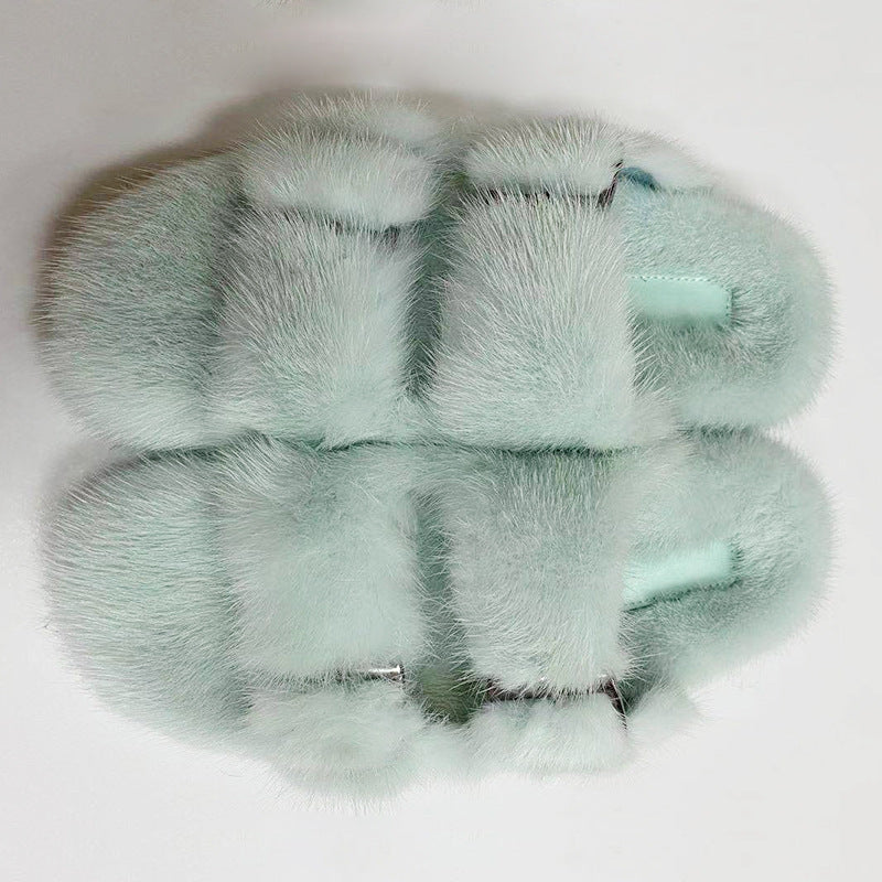 Pair of light green fur slippers on a white background