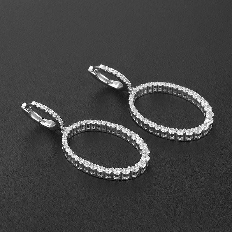 Pair of silver hoop earrings with clear stones on a black background