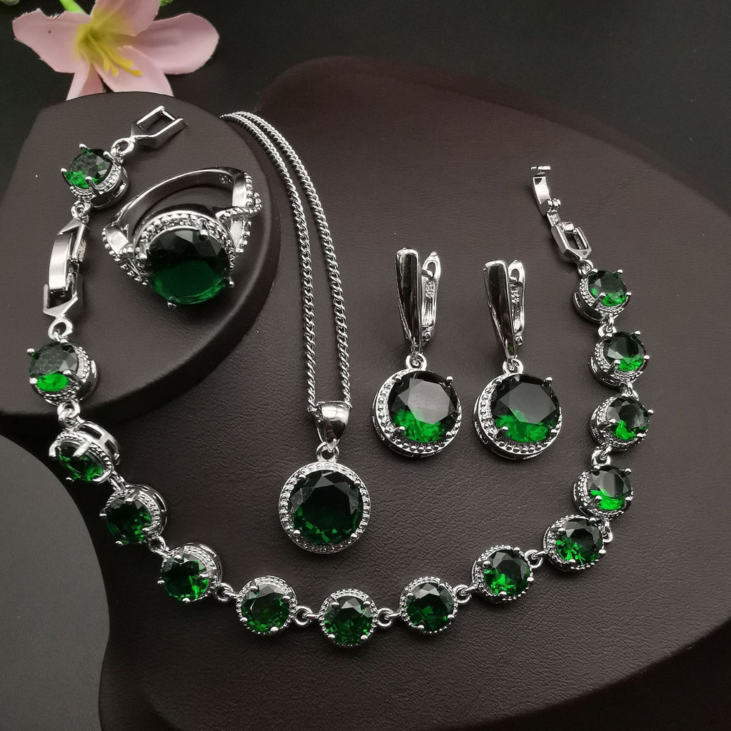 Jewelry set with green gemstones on a dark surface