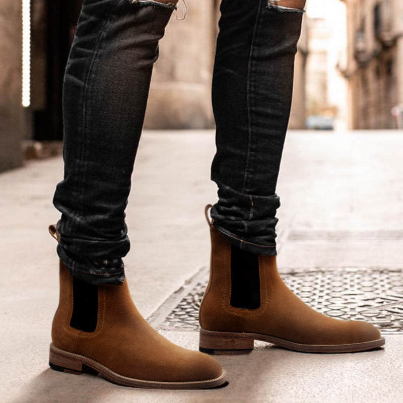Brown Chelsea boots worn with black jeans on a blurred street background