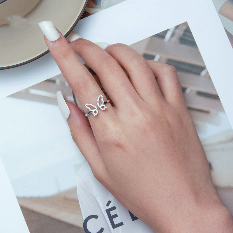 Hand wearing a silver ring with a delicate design on a magazine background