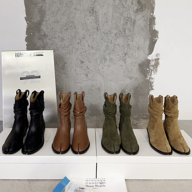 Set of six tabi boots in black, brown, green, and beige on a white surface with a concrete wall background.