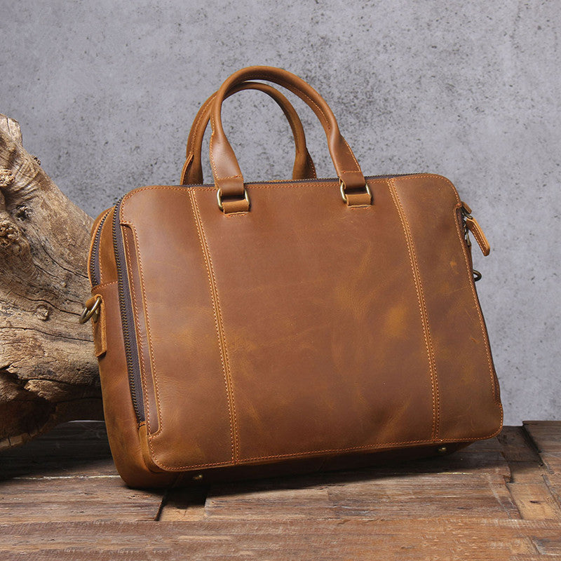 Brown leather briefcase on a wooden surface with a concrete wall background