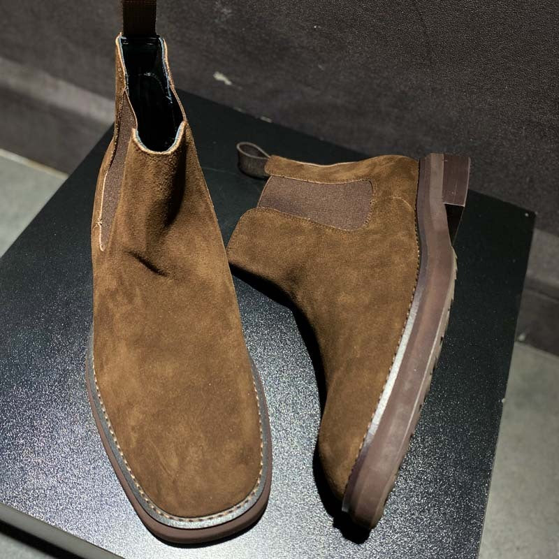 Pair of brown suede ankle boots on a black surface