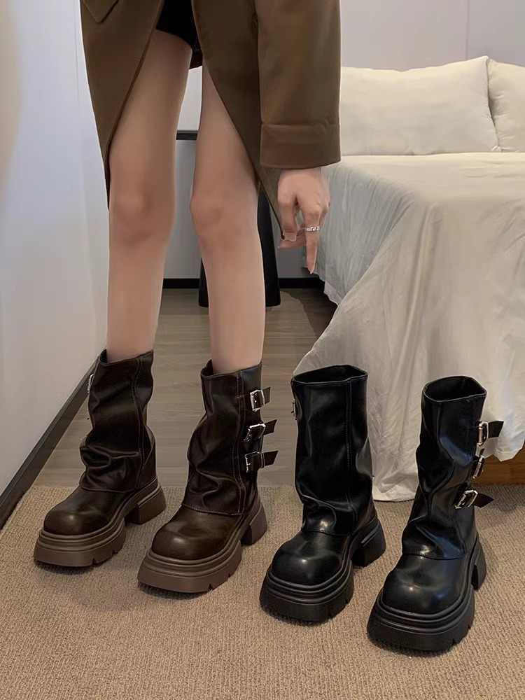 Person wearing brown boots with a matching skirt, standing on a carpeted floor.