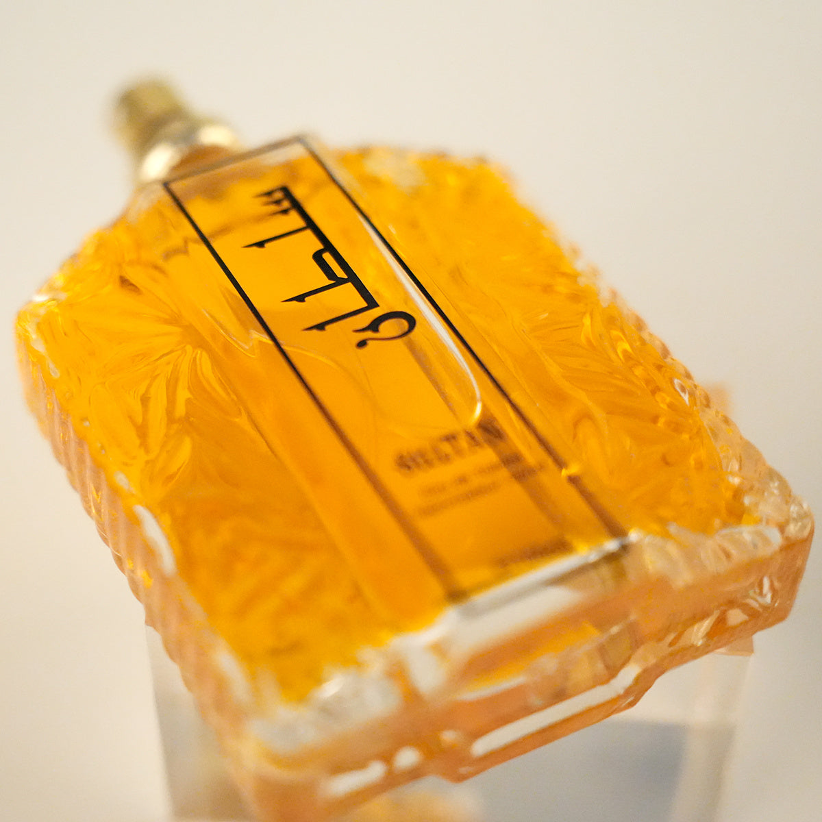 Perfume bottle with a textured surface and visible brand name on a light background