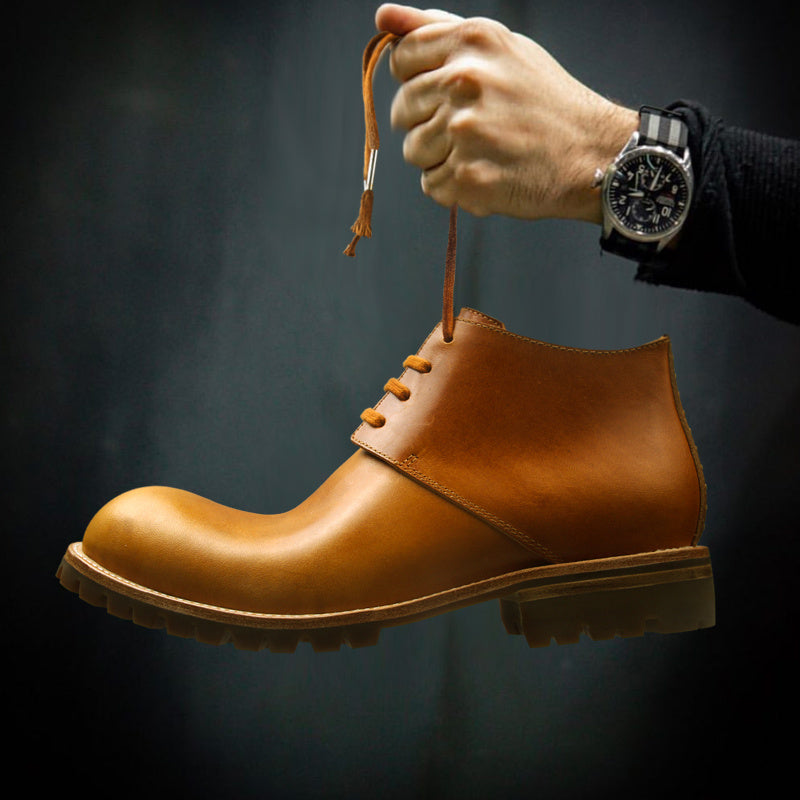 Brown leather boot with a hand tying the laces against a dark background