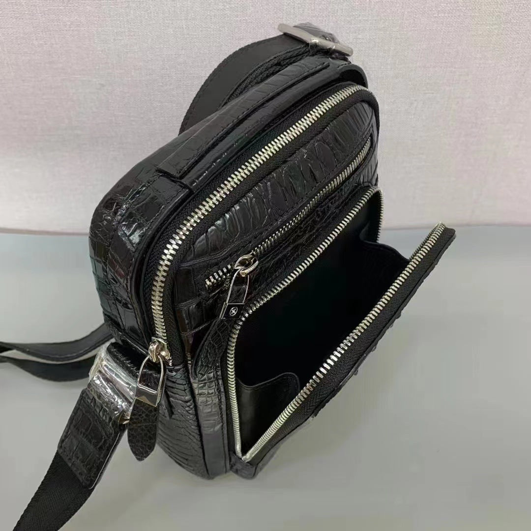 Black textured crossbody bag with zippers on a light gray background