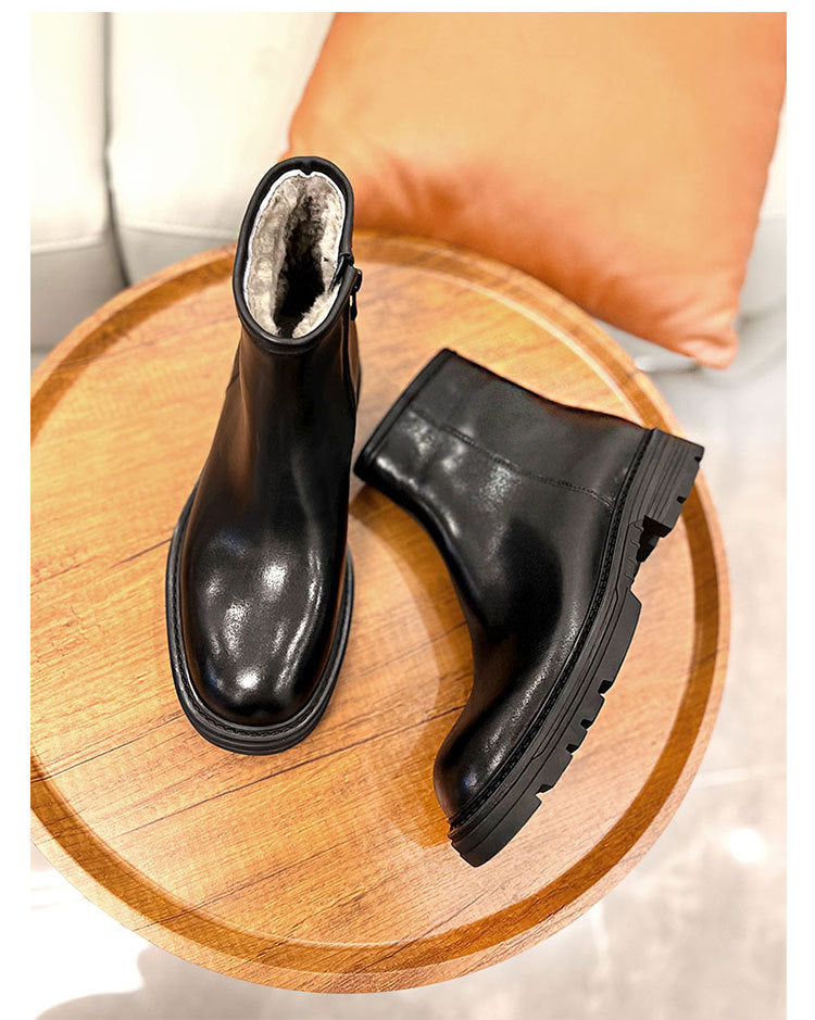 Black leather boots on a wooden surface with a blurred background