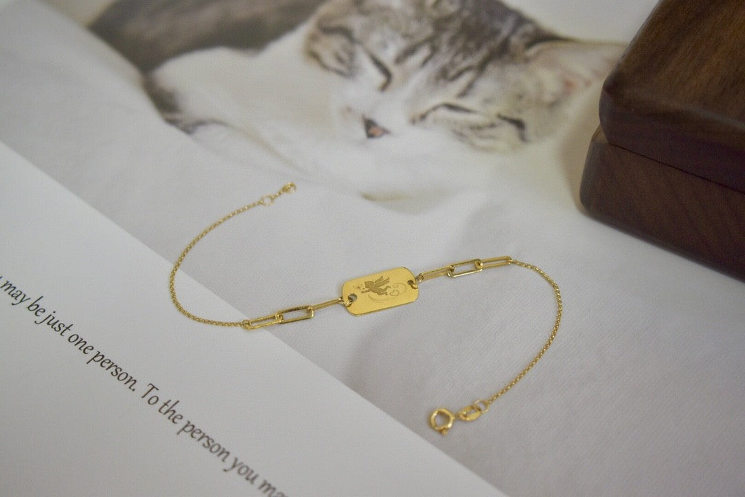 Gold bracelet on an open book with a cat in the background