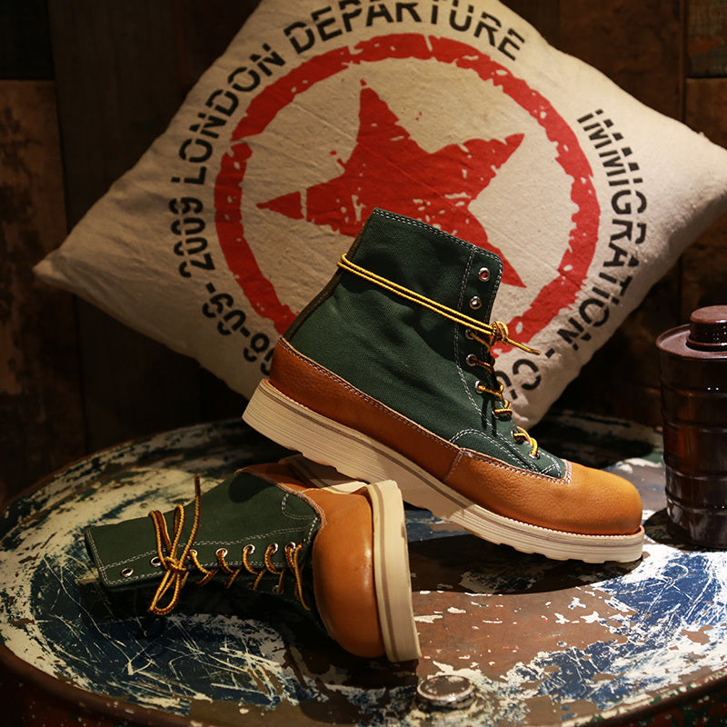 Pair of green and brown boots on a textured surface with a pillow in the background.