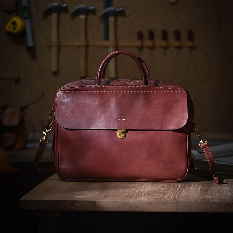 Brown leather bag on a wooden surface with tools in the background