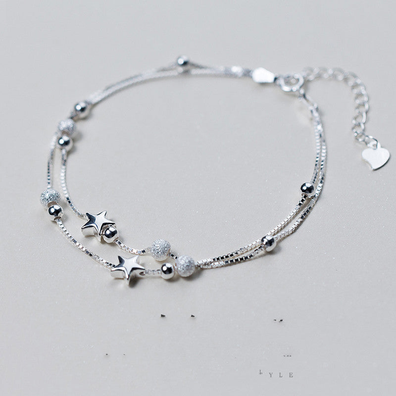 Silver bracelet with various charms on a light gray background
