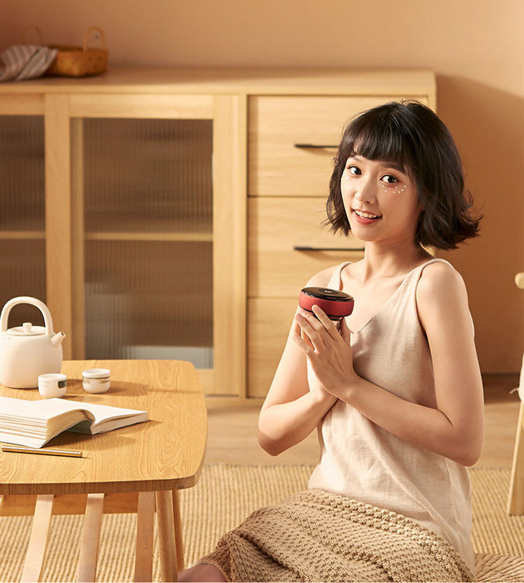 Woman holding a small red bowl in a warm, indoor setting with wooden furniture.