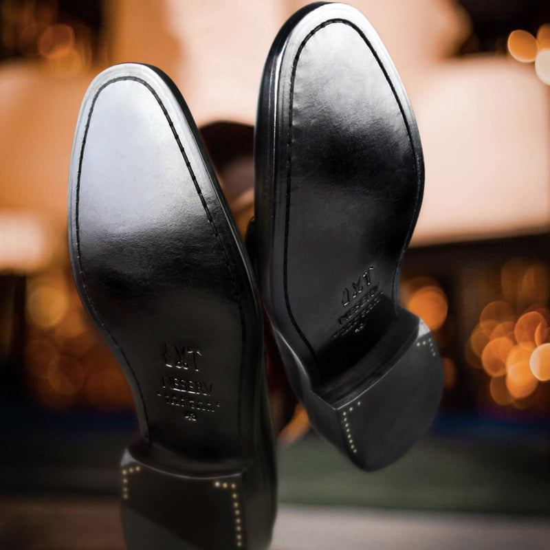 Close-up of black leather shoes with brand name on a blurred background