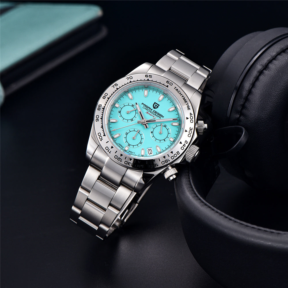 Silver wristwatch with a blue face on a dark surface with headphones in the background