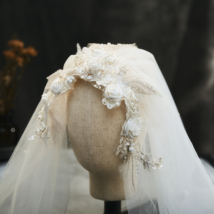 Elegant headpiece with flowers and tulle on a mannequin head against a dark background