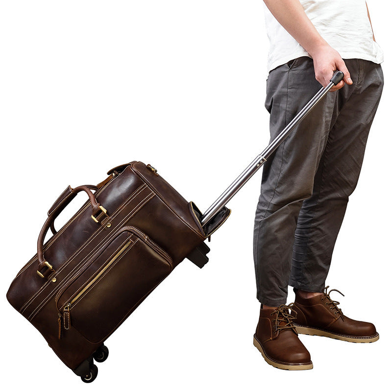 Person pulling a brown leather suitcase on wheels with a white background