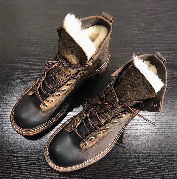 Pair of brown leather boots with white fur lining on a dark wooden surface
