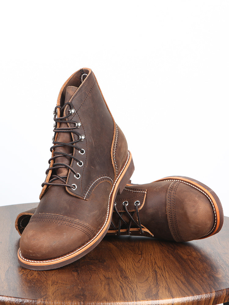 Pair of brown leather boots on a wooden surface with a white background
