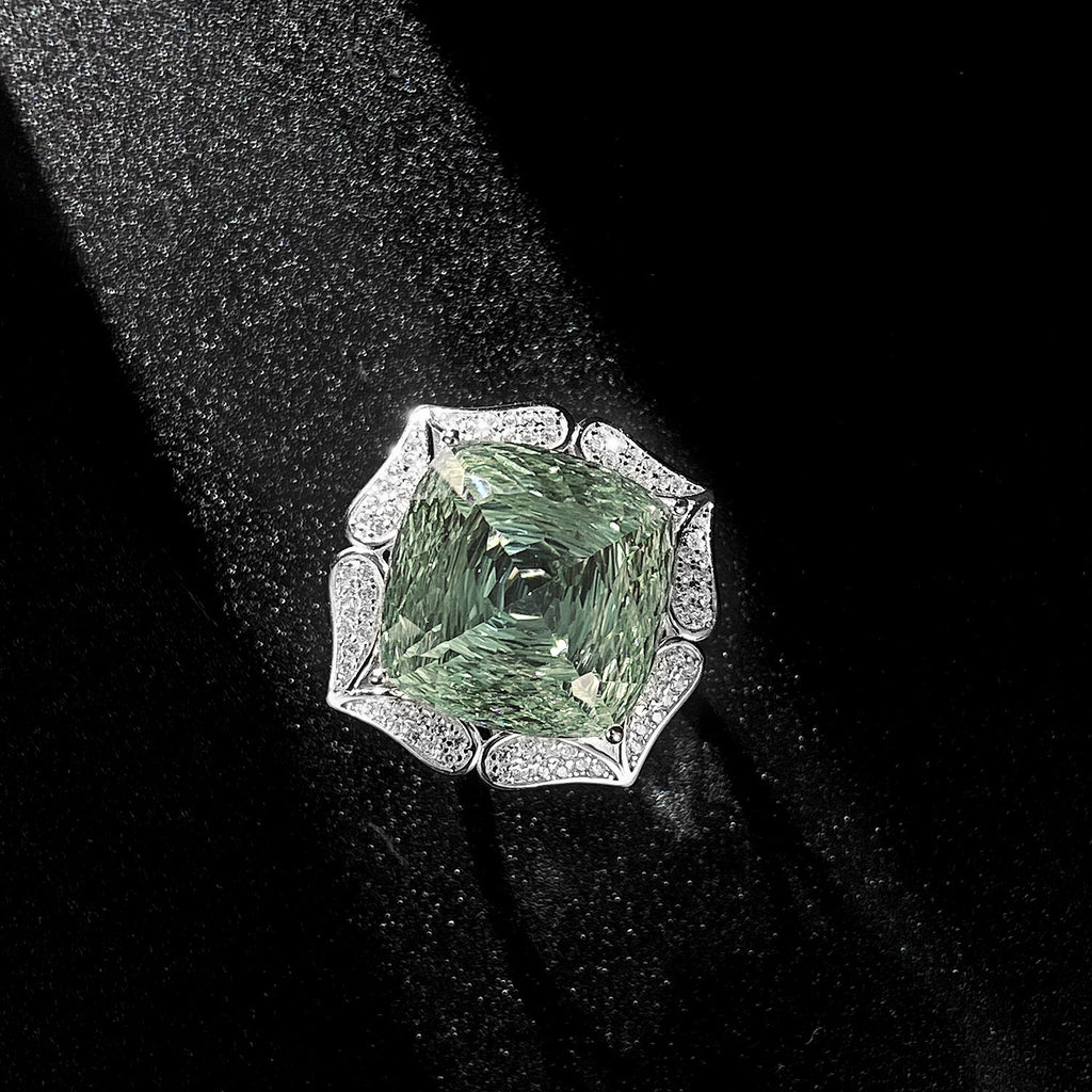 Ring with a green gemstone and diamond-studded band on a black background