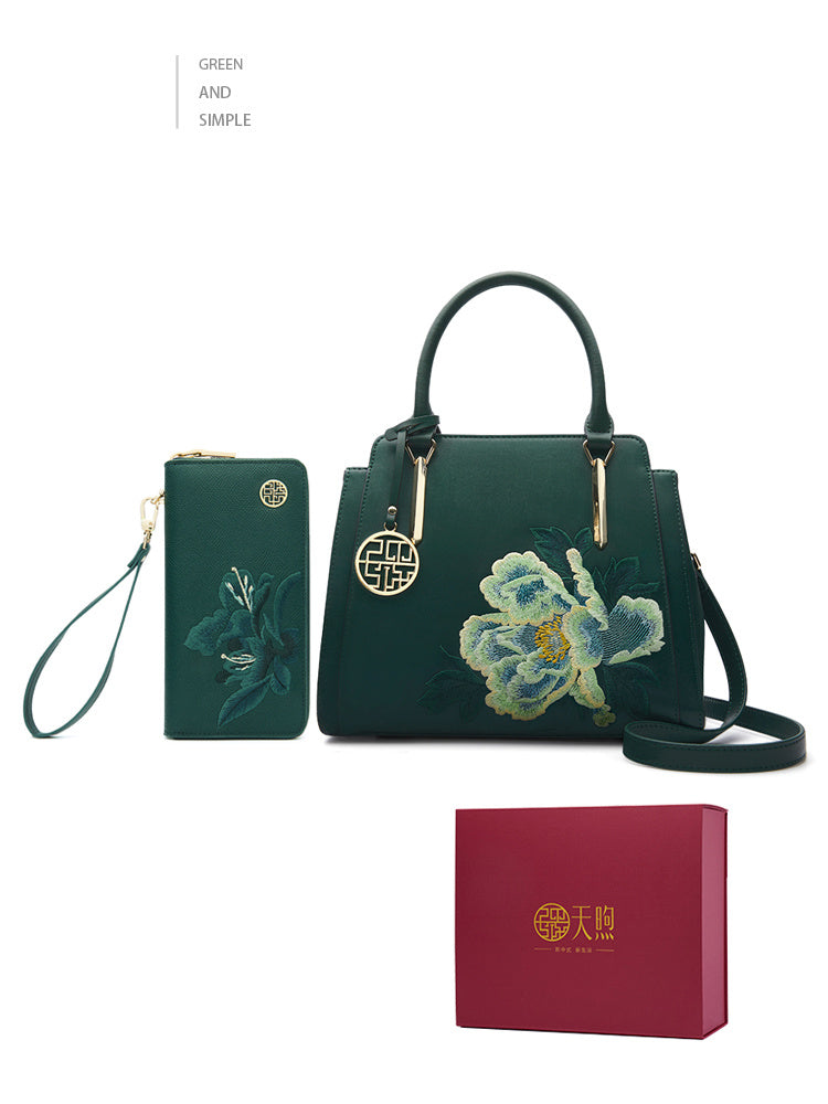 Green handbag with floral embroidery and matching wallet, accompanied by a red box on a white background.