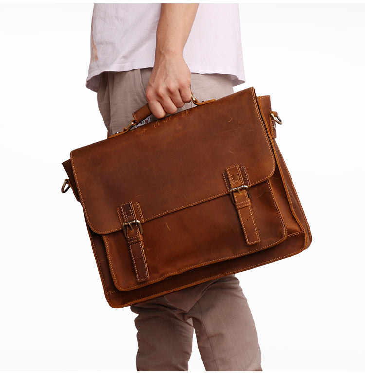 Brown leather briefcase held by a person on a white background