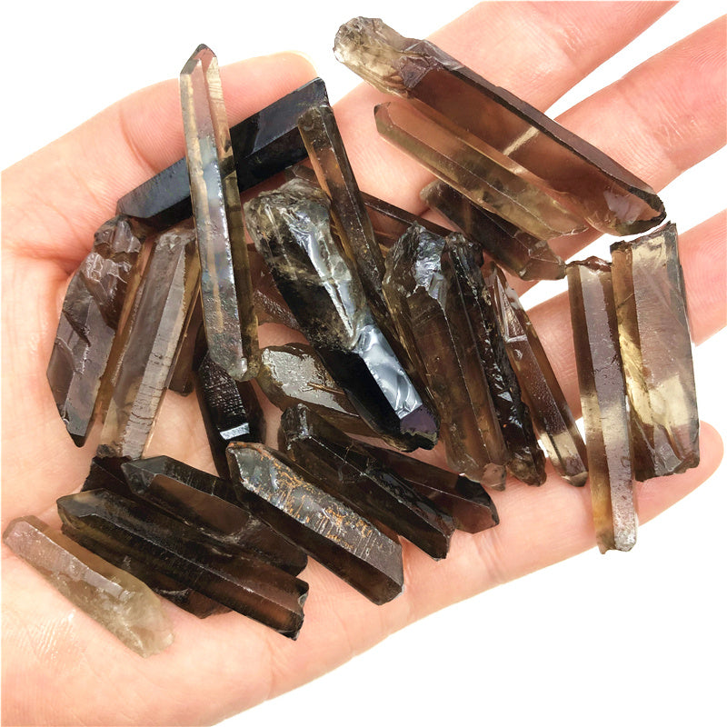 Hand holding a collection of smoky quartz crystals on a white background