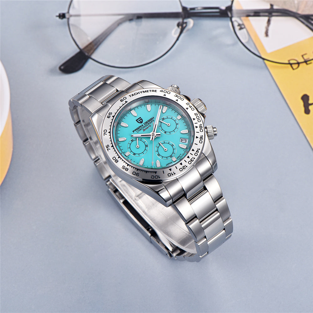Silver watch with a blue face on a light gray surface, with glasses and a yellow card in the background.