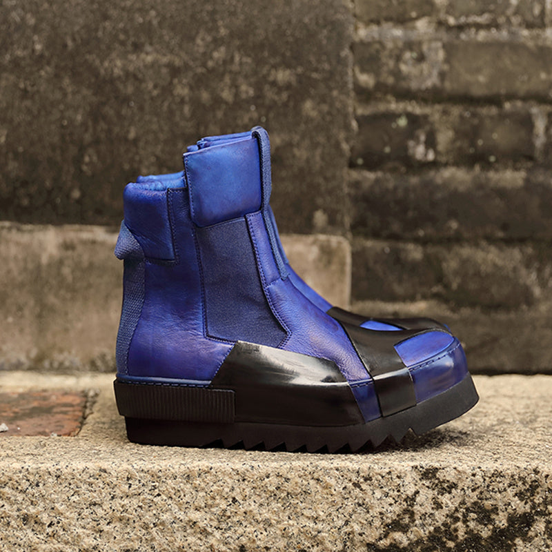 Blue and black boot on a concrete surface with a brick wall background