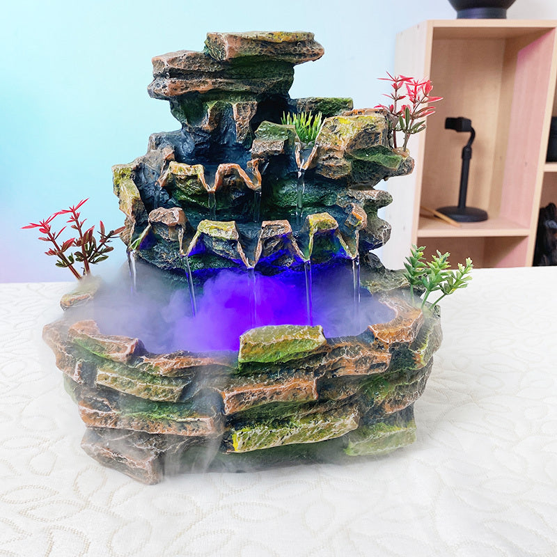 Decorative rock fountain with mist and plants on a white surface