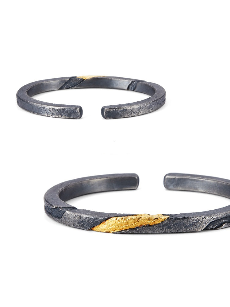Two metallic bracelets with gold accents on a white background
