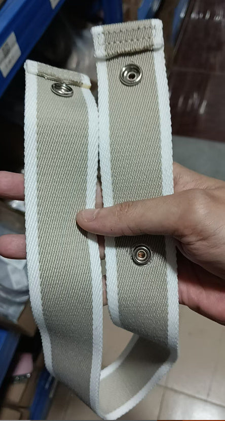 Beige belt strap with metal loops held by a hand against a blurred background