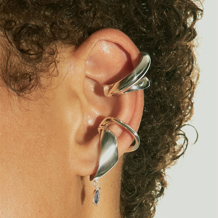 Close-up of an ear wearing silver hoop earrings with a neutral background