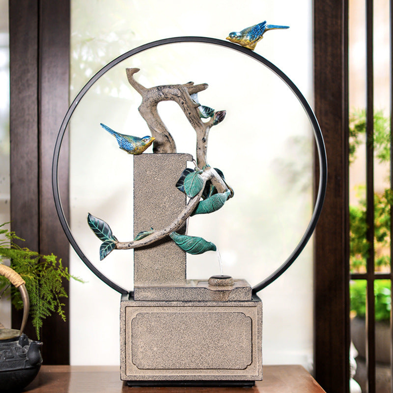 Decorative fountain with birds and leaves on a wooden surface