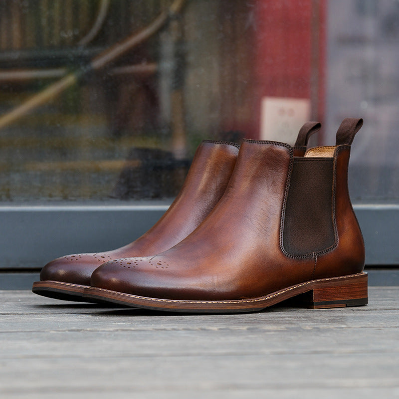Pair of brown leather Chelsea boots on a wooden surface with a blurred background