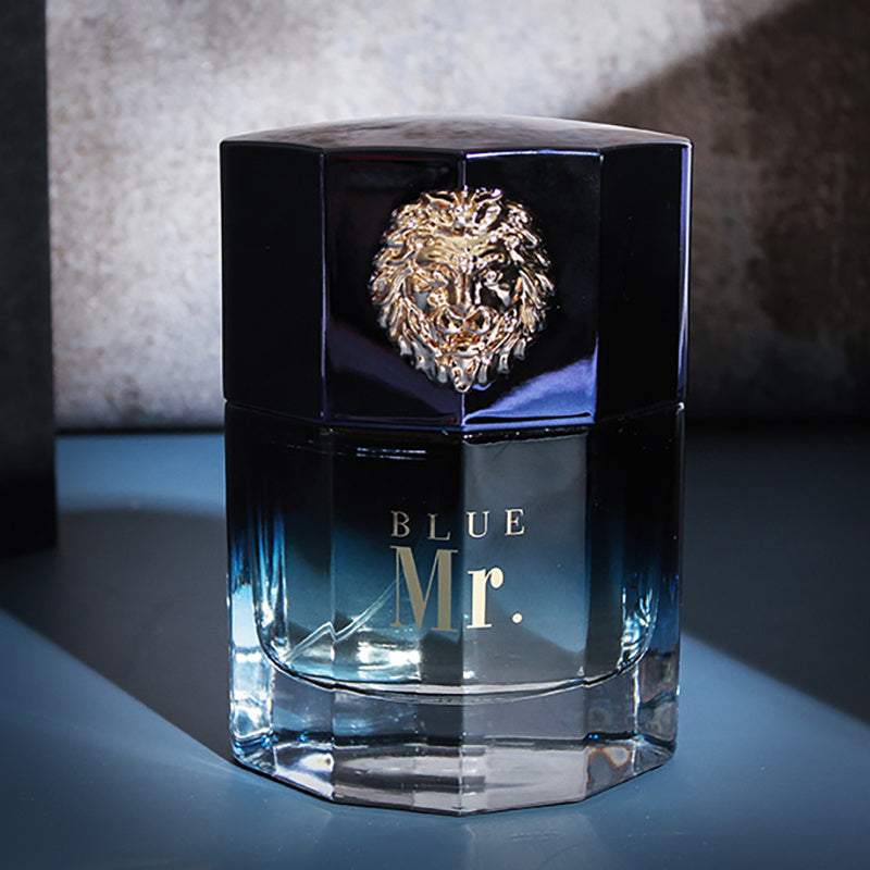 Blue Mr. perfume bottle with a lion emblem on a reflective surface