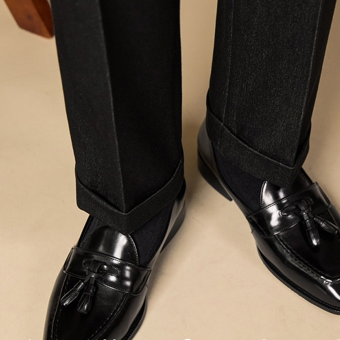 Black dress shoes with loafers worn with black pants on a beige background