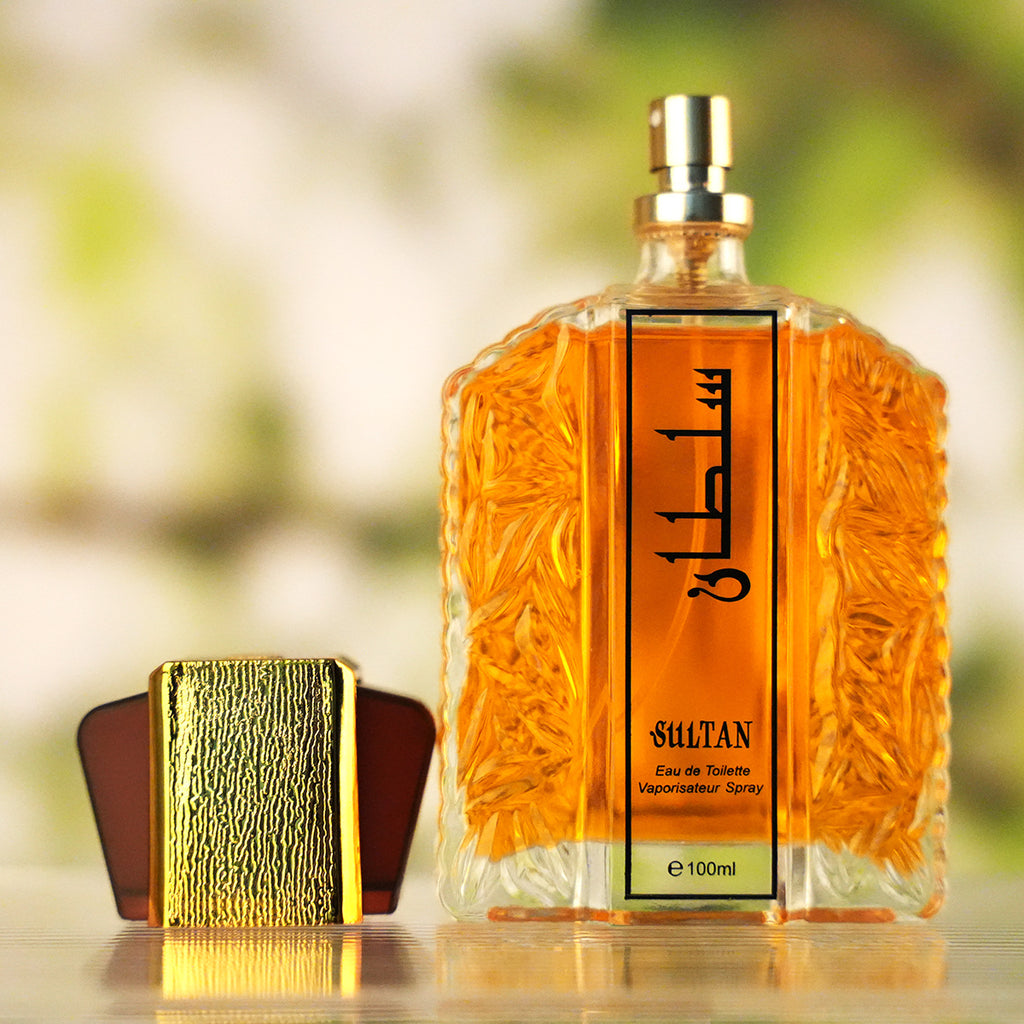 Perfume bottle with gold packaging on a blurred natural background
