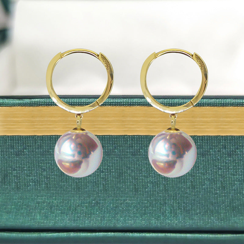Gold hoop earrings with pearl drops on a green box background