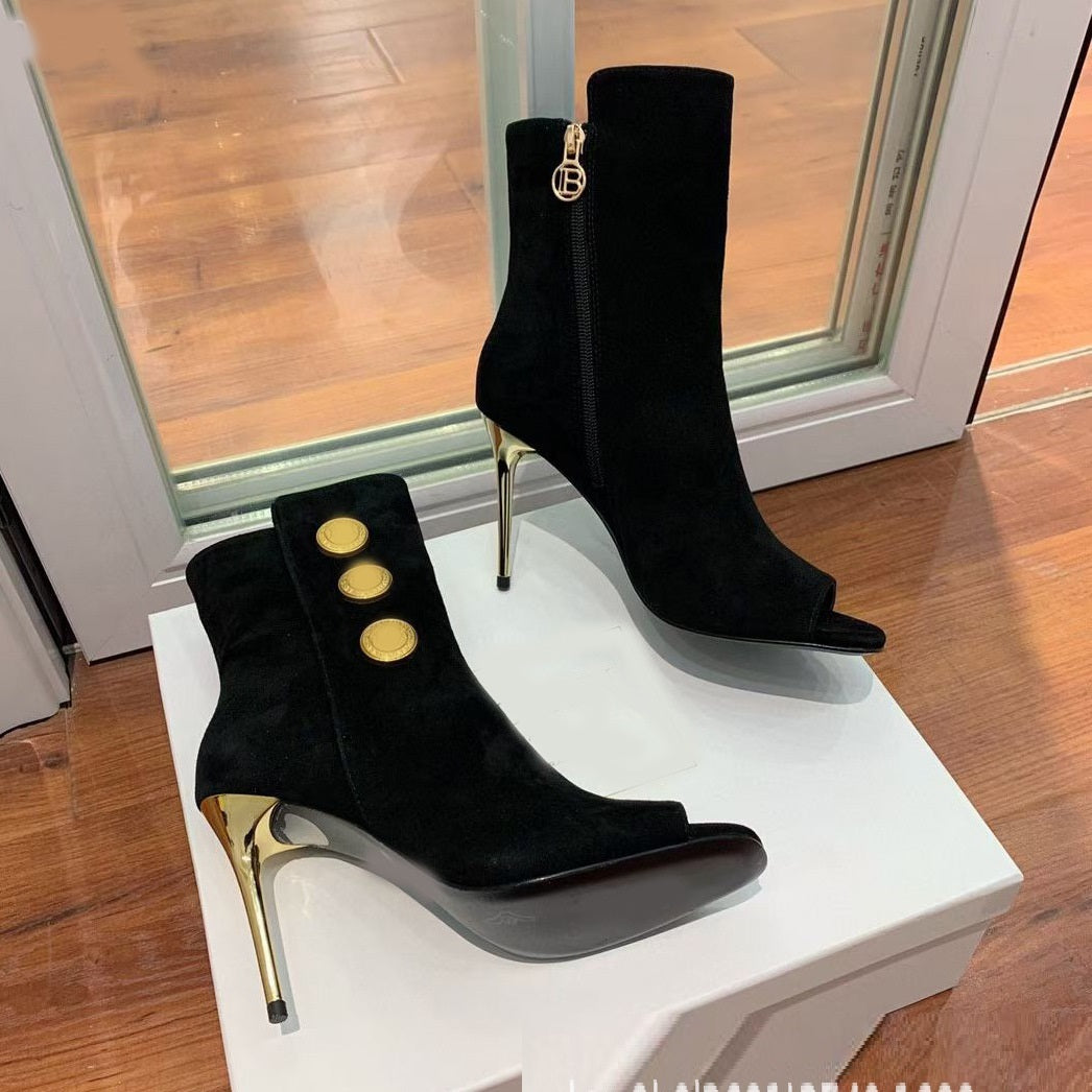 Black high-heeled boots with gold accents on a white platform
