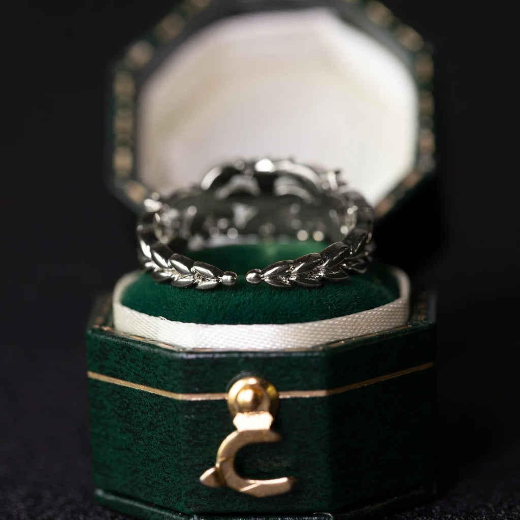 Silver ring in a green jewelry box with a gold clasp on a dark background