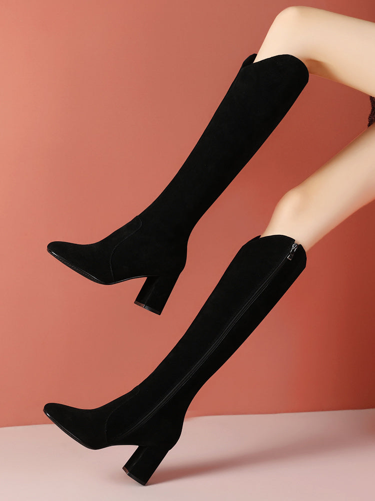 Black knee-high boots worn by a person against a pink background